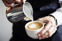 Investing in coffee; image of a barista pouring cream into coffee